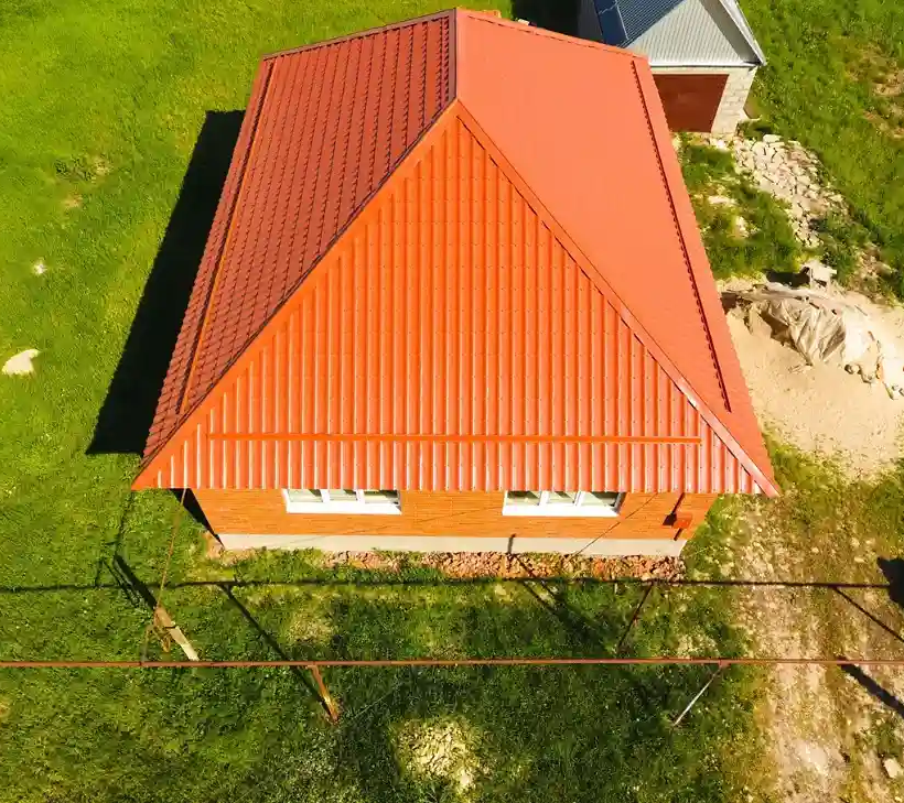 Aerial view of house roof painting with orange metal roof