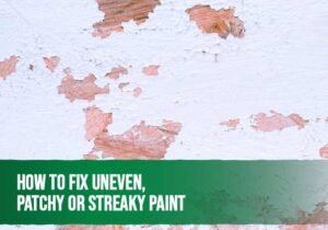 Painter fixing uneven and patchy paint on a wall using a roller for a smooth finish.