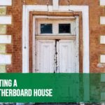 Painter applying fresh exterior paint to a weatherboard house after proper surface preparation.