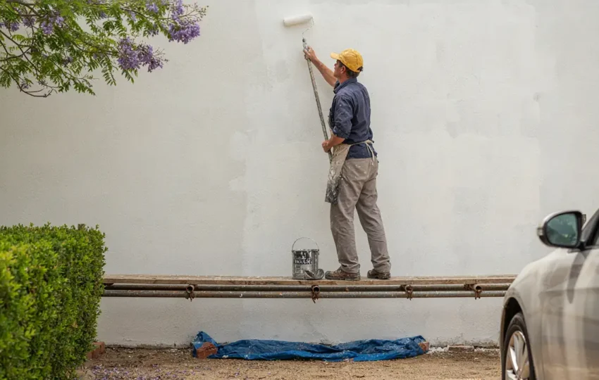 Professional painter painting the exterior of a rendered Adelaide home showing quality workmanship and proper preparation with drop sheets